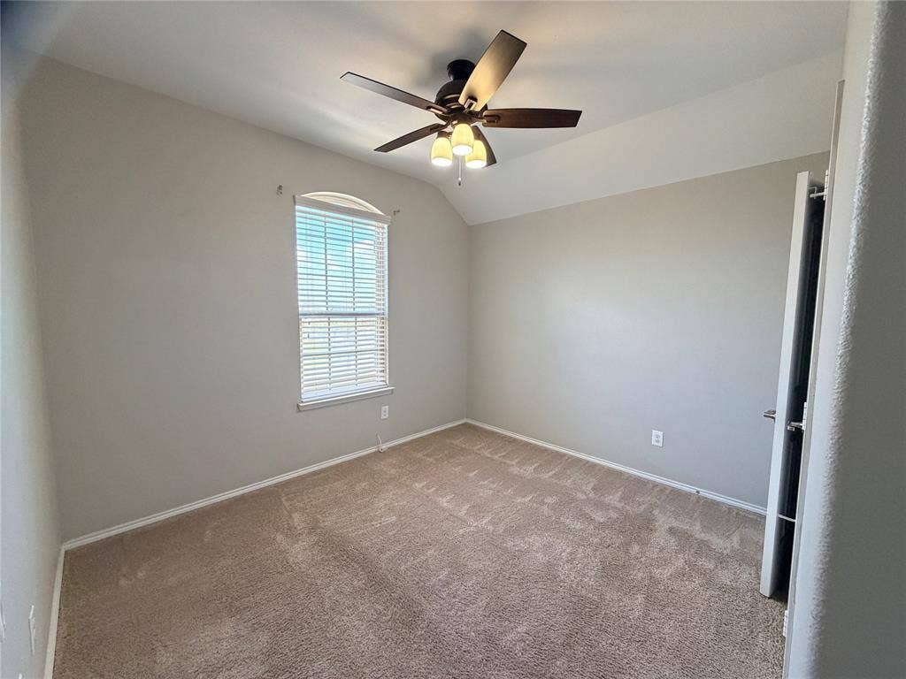 4103 Portrush Drive, Heartland, TX 75126 Arched window with blinds, ceiling fan with integrated lighting, neutral wall paint, and carpet flooring
