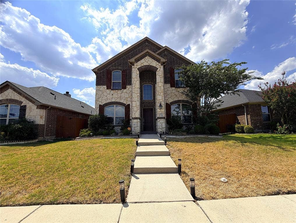 4103 Portrush Drive, Heartland, TX 75126 Brick and stone exterior with arched windows, mature landscaping, and a concrete pathway with integrated lighting