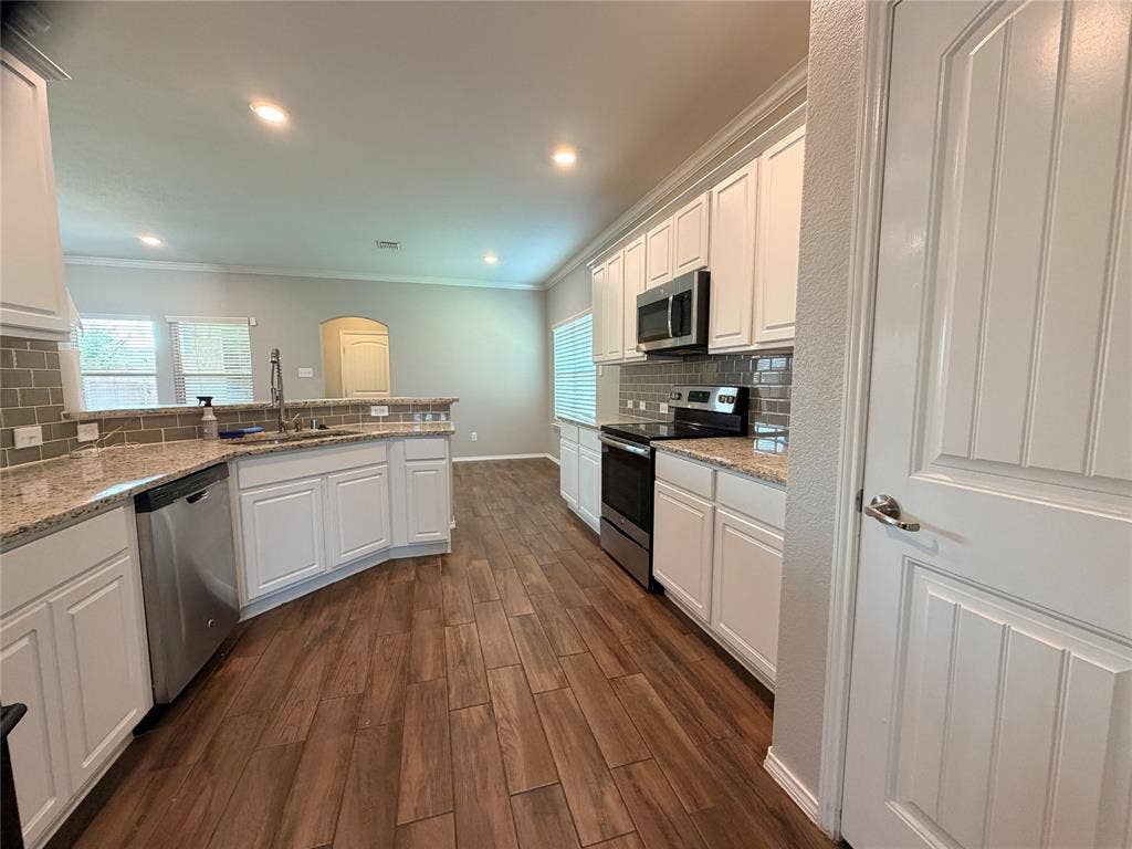 4103 Portrush Drive, Heartland, TX 75126 Kitchen featuring white cabinetry, granite countertops, a subway tile backsplash, stainless steel appliances, and wood-finish flooring