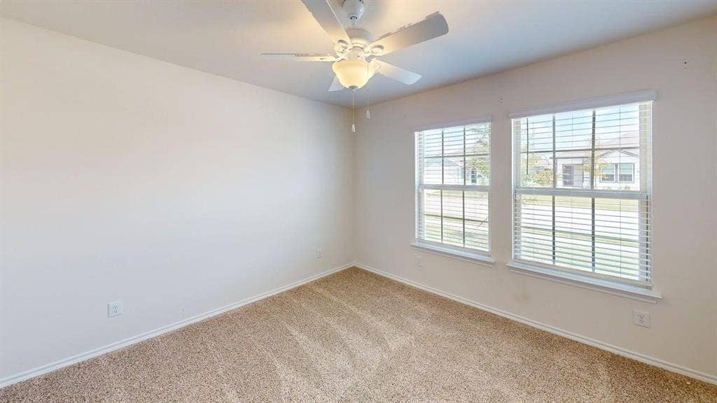 6534 Whitecap Drive, Princeton, TX 75407 Carpeted room featuring two double-hung windows with blinds, a ceiling fan with light, and neutral wall paint