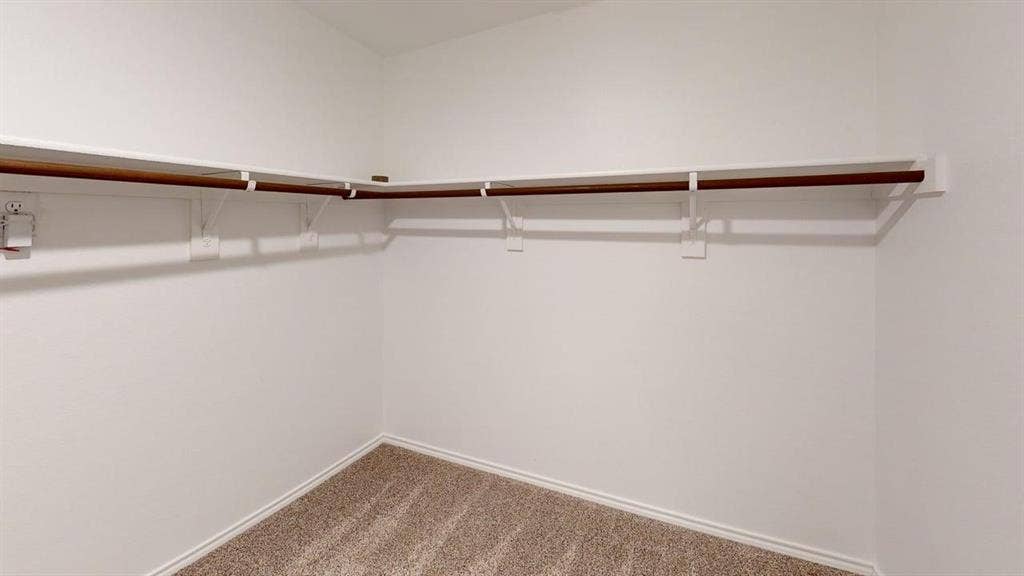 6534 Whitecap Drive, Princeton, TX 75407 Corner built-in shelving with hanging rod, light-colored walls, and textured carpet flooring