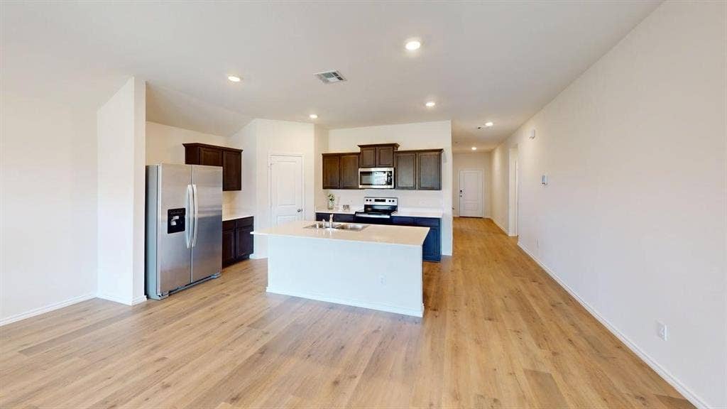 6534 Whitecap Drive, Princeton, TX 75407 Open-concept living area featuring wood-finish flooring, recessed lighting, a kitchen island, and stainless steel appliances
