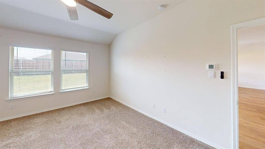 6534 Whitecap Drive, Princeton, TX 75407 Carpeted flooring, vaulted ceiling, dual windows with blinds, ceiling fan with integrated lighting, and a wall-mounted thermostat