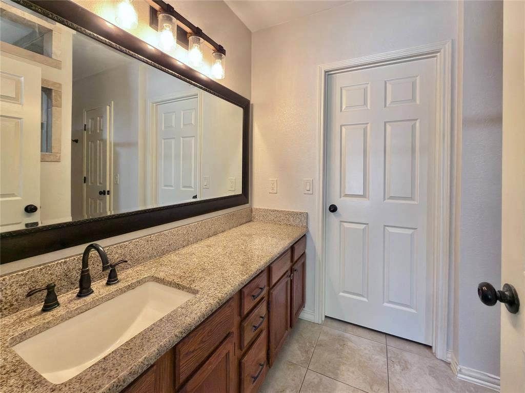 418 Newberry Street, Grand Prairie, TX 75052 Spacious vanity featuring an integrated sink, dark bronze fixtures, and a granite-style countertop