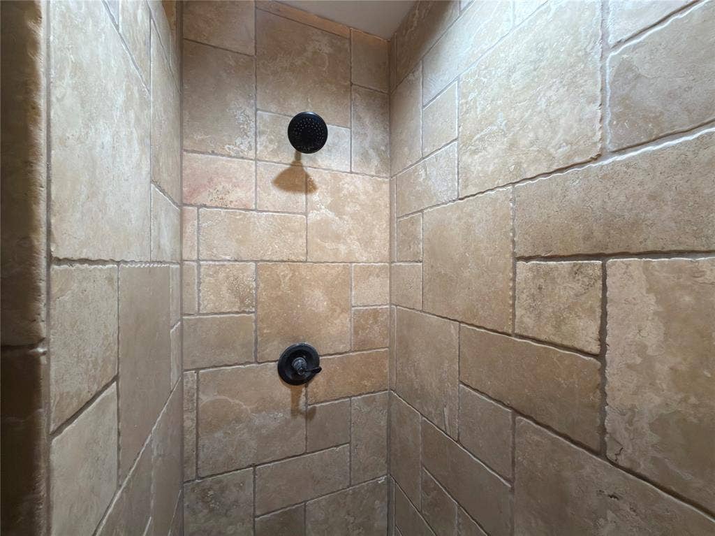 418 Newberry Street, Grand Prairie, TX 75052 Shower enclosure with natural stone-look tile, dark bronze-finish shower head, and dark bronze-finish shower controls