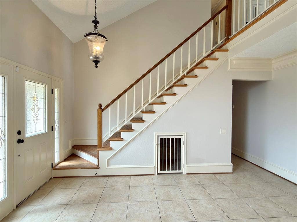 418 Newberry Street, Grand Prairie, TX 75052 Two-story foyer featuring a tile floor, wood staircase with white balusters, and a decorative glass entry door with sidelights