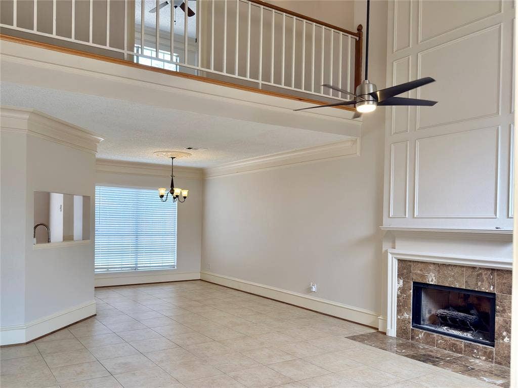 418 Newberry Street, Grand Prairie, TX 75052 Two-story living area featuring a fireplace with a stone surround, decorative wall paneling, and a loft overlook