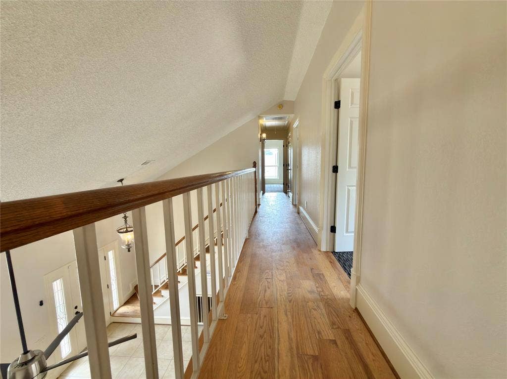 418 Newberry Street, Grand Prairie, TX 75052 Wood-finish flooring throughout the hallway, white painted walls, and a white railing with a wood-finish handrail
