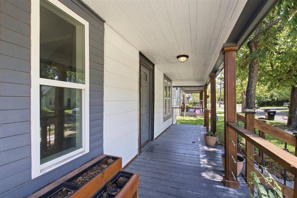 1812 Oneal Street, Greenville, TX 75401 Covered front porch featuring wood-finish columns, a painted wood railing, and a beadboard ceiling with a flush-mount light fixture