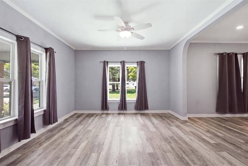 1812 Oneal Street, Greenville, TX 75401 Wood-finish flooring, crown molding, ceiling fan, multiple windows, and arched doorway