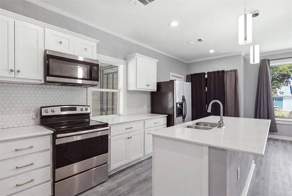 1812 Oneal Street, Greenville, TX 75401 Kitchen featuring white cabinetry, stainless steel appliances, a white hexagonal tile backsplash, white countertops, and wood-finish flooring