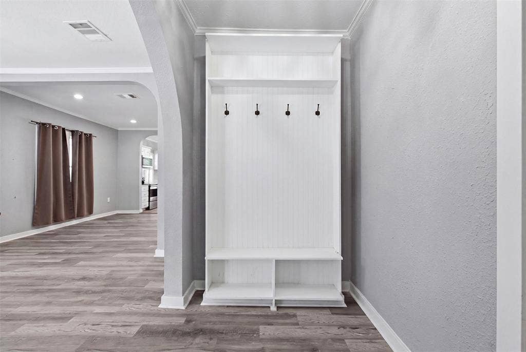 1812 Oneal Street, Greenville, TX 75401 Built-in hall tree with beadboard backing and shelving, wood-finish flooring, recessed lighting, and arched doorways