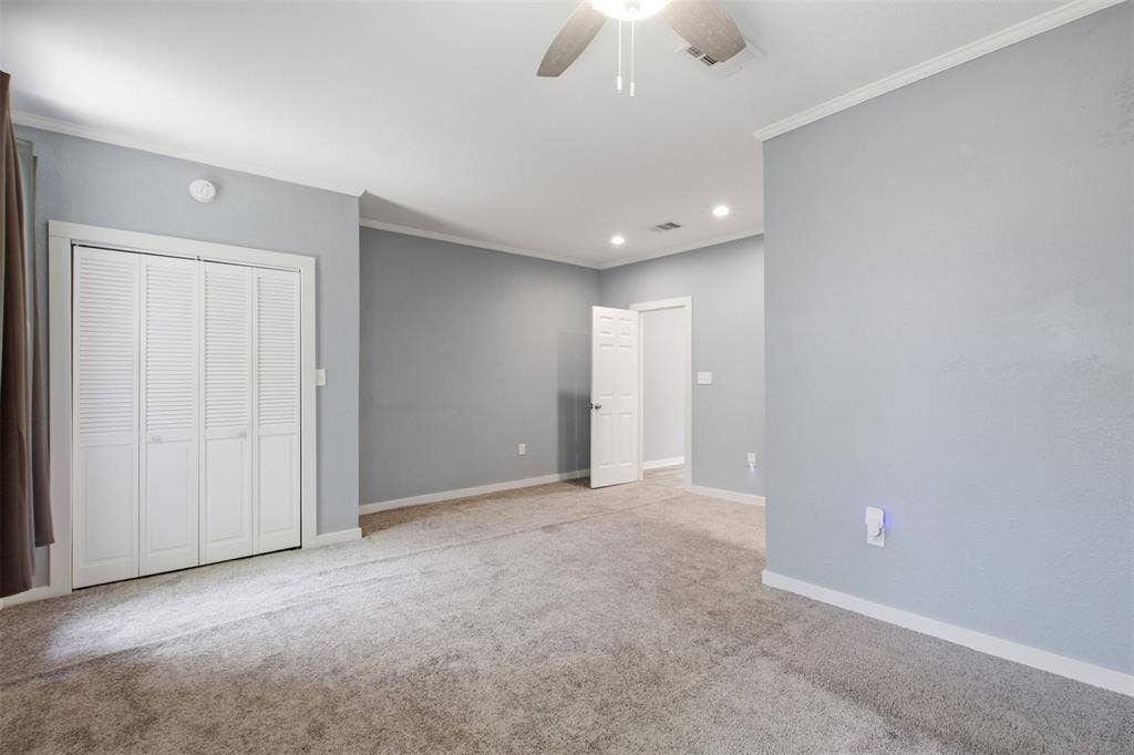 1812 Oneal Street, Greenville, TX 75401 Recessed ceiling lighting, crown molding, ceiling fan, bi-fold closet doors, and light gray wall paint