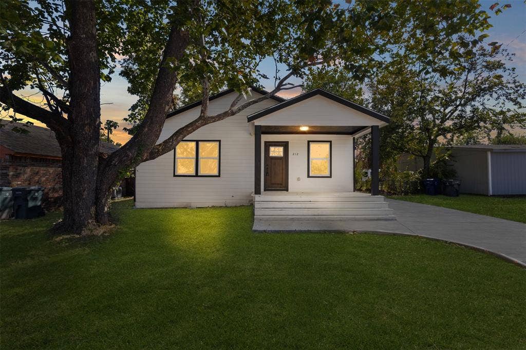212 E Marguerita Drive, Garland, TX 75040 White siding exterior with a dark trim roofline, covered front porch, concrete steps, and a concrete pathway