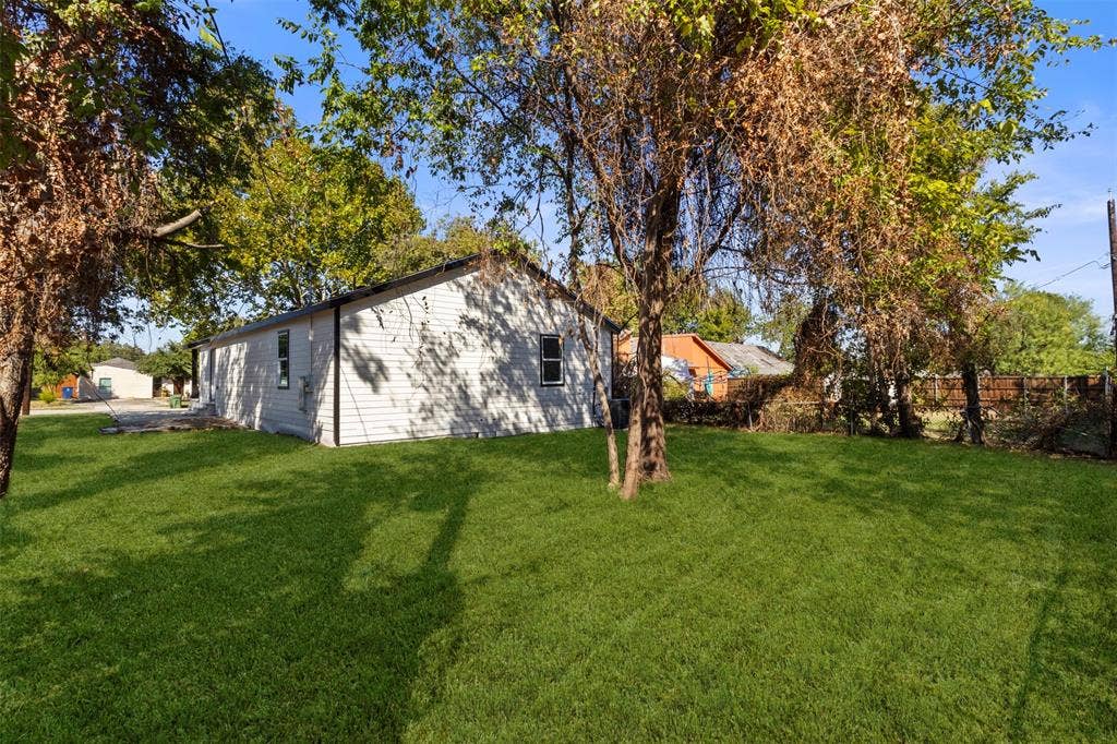 212 E Marguerita Drive, Garland, TX 75040 Expansive grassy yard with mature trees and a white siding exterior