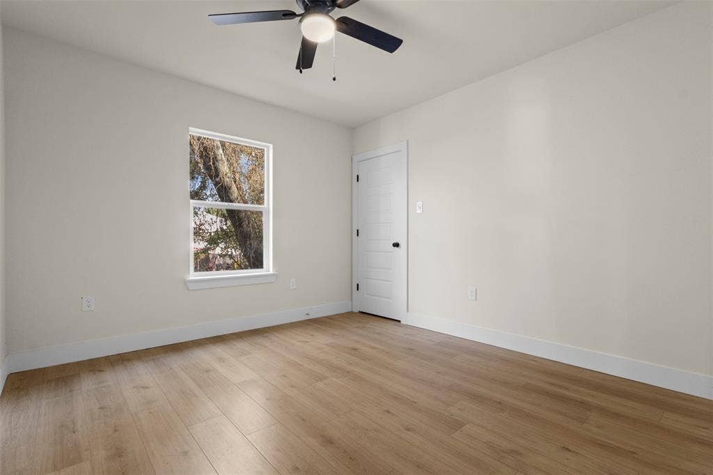 212 E Marguerita Drive, Garland, TX 75040 Neutral-toned walls with wood-finish flooring, a ceiling fan, and a white interior door