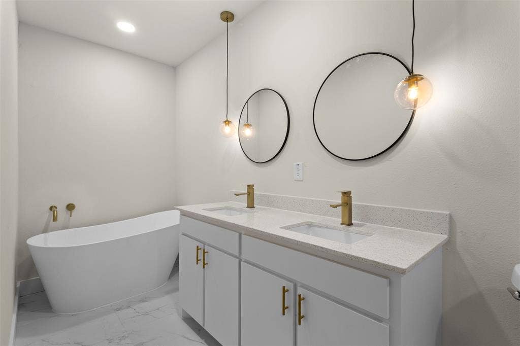 212 E Marguerita Drive, Garland, TX 75040 Double vanity with quartz countertop, dual undermount sinks, and gold-finish fixtures