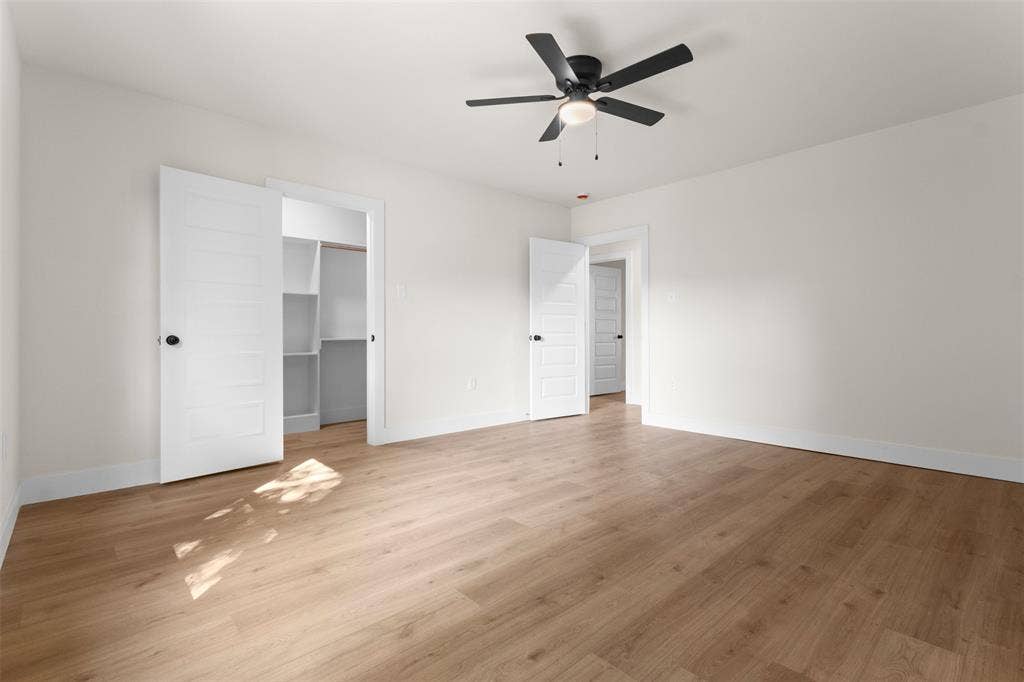 212 E Marguerita Drive, Garland, TX 75040 Recessed shelving, wood-finish flooring, white paneled doors, ceiling fan with integrated lighting, and neutral wall tones