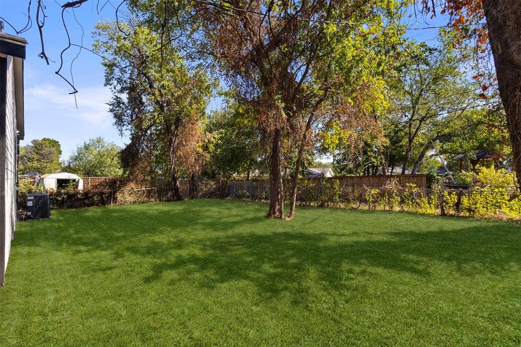 212 E Marguerita Drive, Garland, TX 75040 Expansive grassy yard with mature trees and a privacy fence