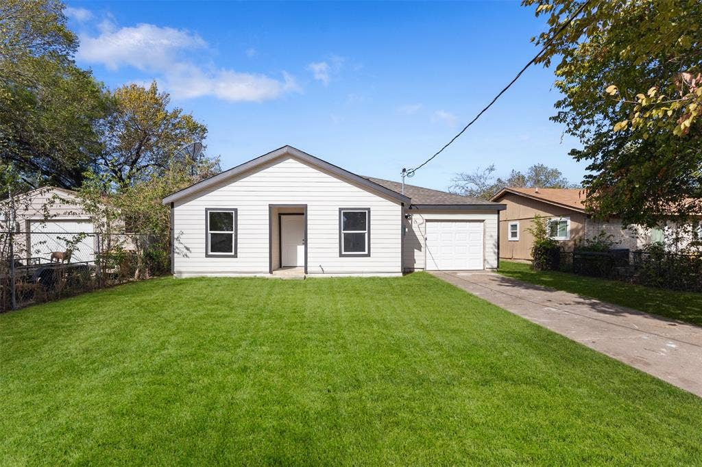 Single-story residence featuring light-colored horizontal siding, a concrete driveway, an attached garage, and a level lawn