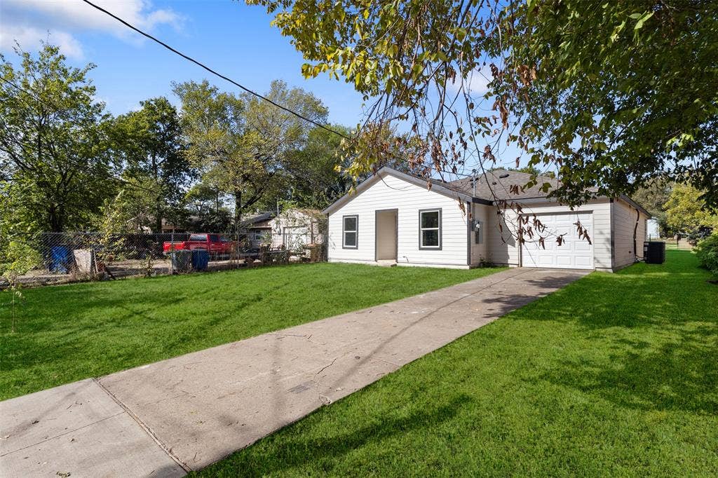 Single-story residence featuring horizontal lap siding, an attached garage, and a paved concrete driveway situated on a grass-covered lot