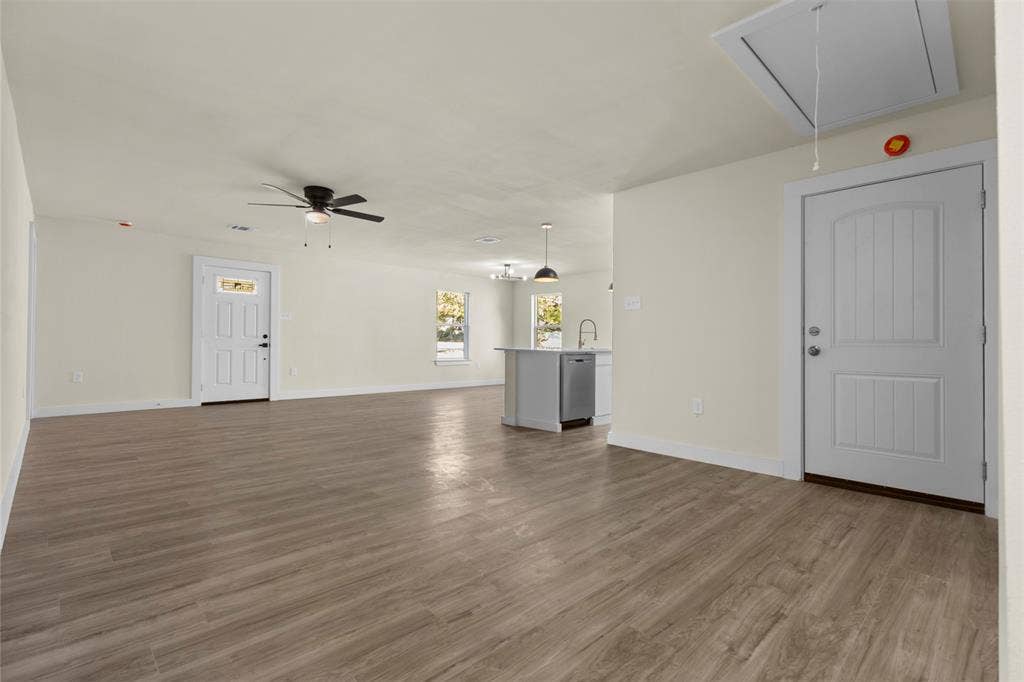 Open-concept interior featuring wood-finish flooring, ceiling fan, recessed lighting, and white panel doors