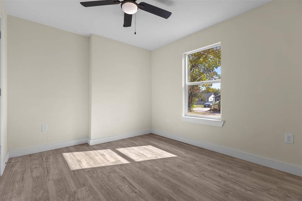 Neutral-toned interior space featuring wood-finish flooring, a ceiling fan with integrated lighting, and a single-hung window