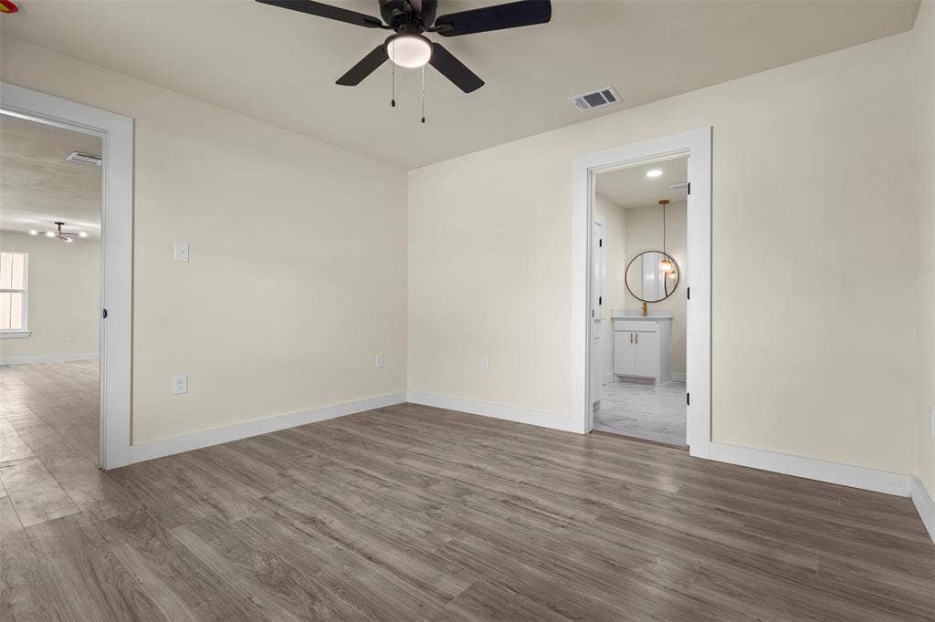 Neutral-toned interior featuring wood-finish flooring, a ceiling fan with integrated lighting, and white door casings