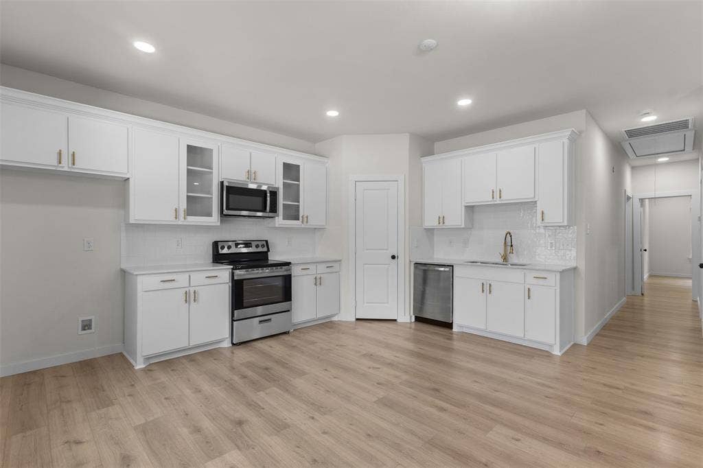333 Levant Avenue, Dallas, TX 75217 Kitchen featuring white cabinetry, stainless steel appliances, wood-finish flooring, recessed lighting, and a subway tile backsplash