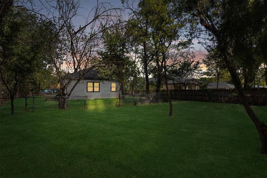 333 Levant Avenue, Dallas, TX 75217 Expansive rear yard featuring a manicured lawn, established trees, and perimeter fencing