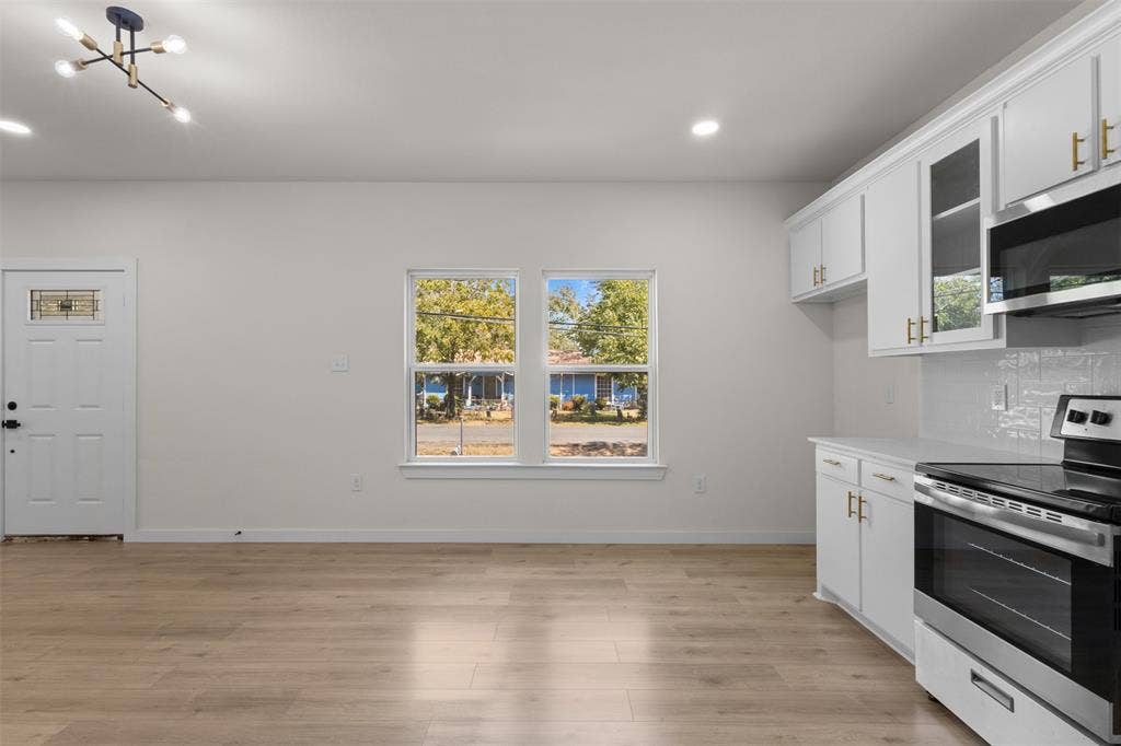333 Levant Avenue, Dallas, TX 75217 Wood-finish flooring, white cabinetry with gold-tone hardware, stainless steel range, built-in microwave, and recessed lighting