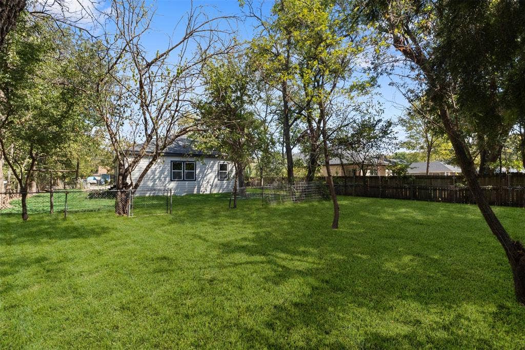 333 Levant Avenue, Dallas, TX 75217 Expansive green lawn with mature trees and a wood privacy fence