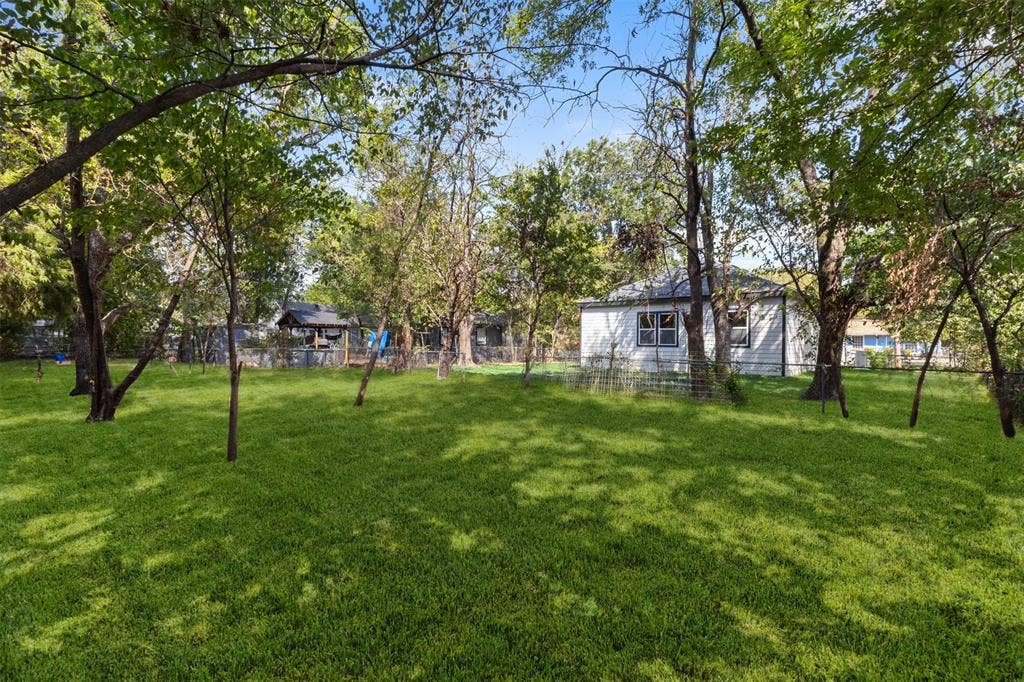 333 Levant Avenue, Dallas, TX 75217 Expansive green lawn with mature trees and a single-story residence featuring light-colored siding
