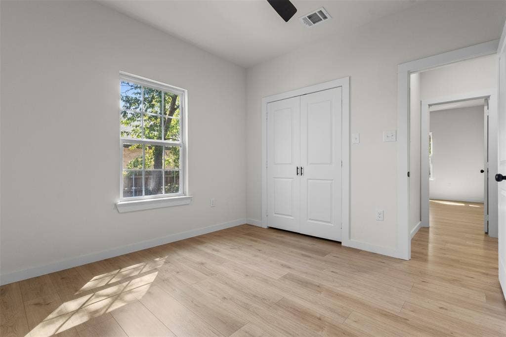 333 Levant Avenue, Dallas, TX 75217 Wood-finish flooring, white walls, double-door closet, window with exterior foliage, and a ceiling fan