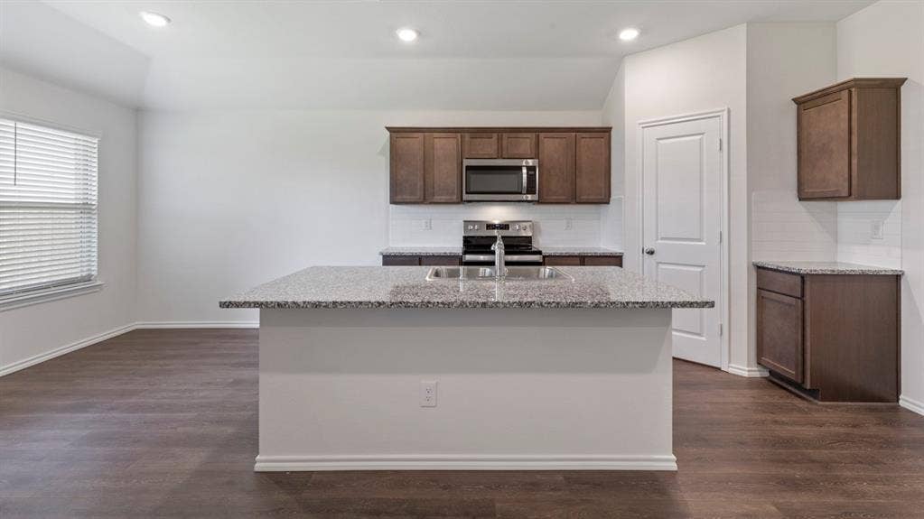 193 Brooks Street, Bullard, TX 75757 Kitchen island with a double basin sink, stainless steel appliances, dark wood-finish cabinetry, and wood-finish flooring