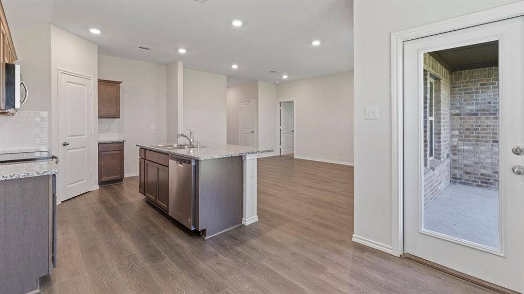 193 Brooks Street, Bullard, TX 75757 Open concept living space with recessed lighting, wood-finish flooring, and a kitchen island featuring a double-basin sink