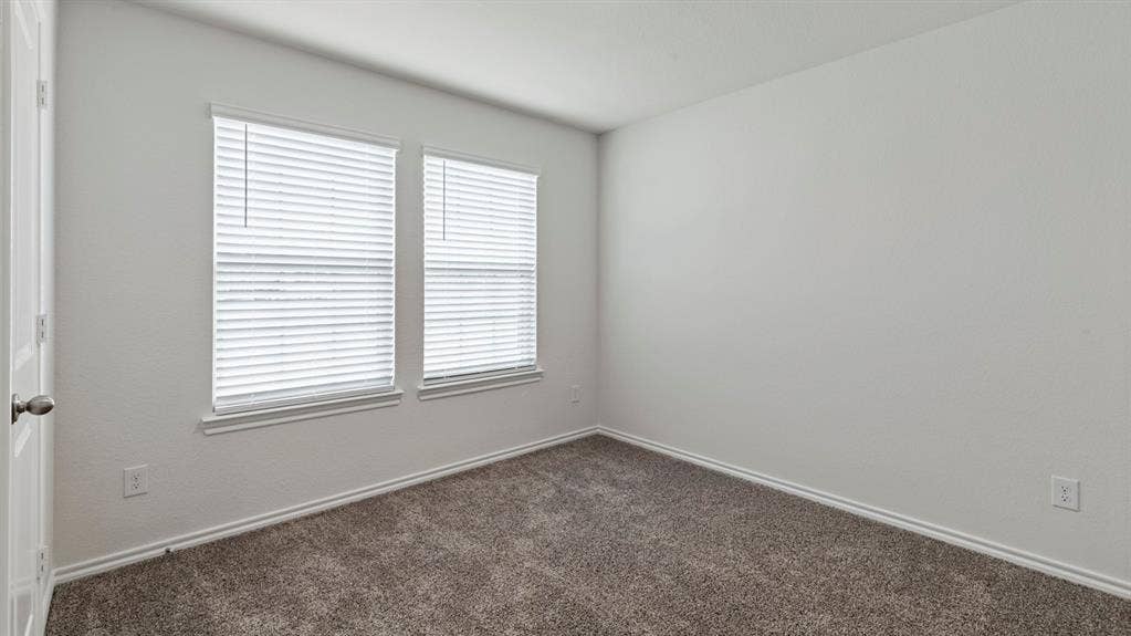 205 Brooks Street, Bullard, TX 75757 Neutral wall paint, two windows with blinds, and neutral carpeting