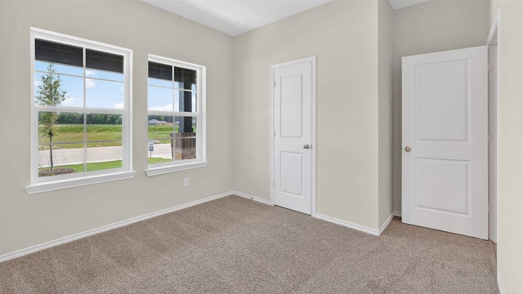 201 Brooks Street, Bullard, TX 75757 Beige wall paint, two white paneled doors, two single-hung windows, and light brown carpeting