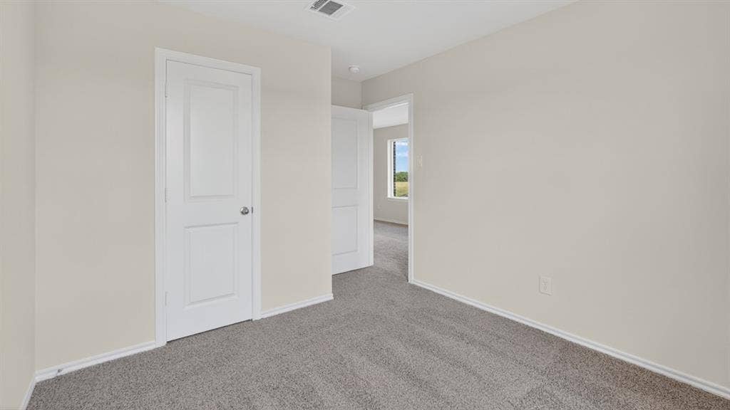 201 Brooks Street, Bullard, TX 75757 Plush gray carpeting with light-toned walls, white trim, and a white two-panel door with a brushed nickel knob