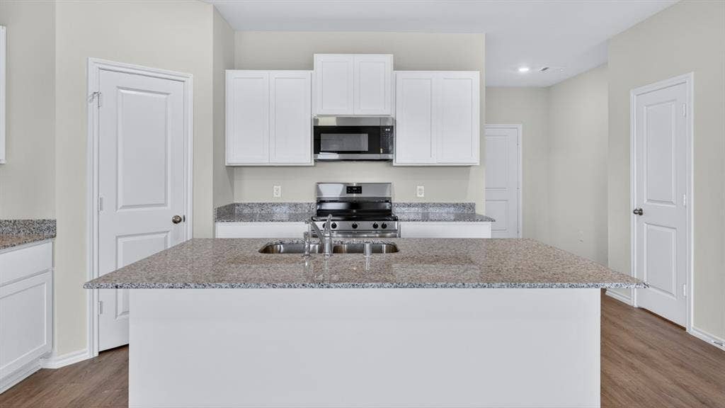 201 Brooks Street, Bullard, TX 75757 Kitchen featuring a center island, white cabinetry, granite countertops, and stainless steel appliances