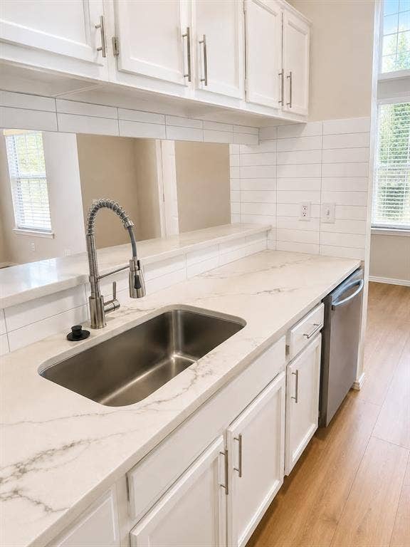 4952 Berridge Lane, Dallas, TX 75227 Kitchen featuring white cabinetry, a stainless steel sink with a pull-down faucet, white patterned countertops, a white subway tile backsplash, and wood-finish flooring