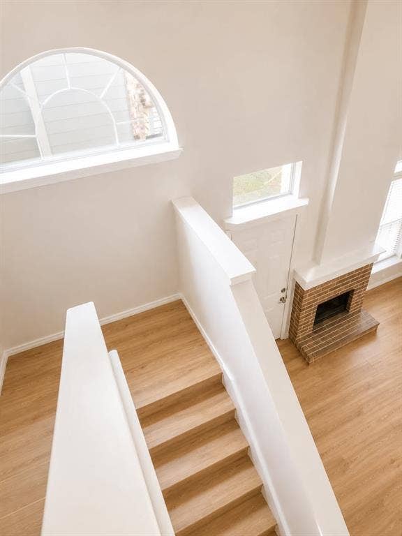 4952 Berridge Lane, Dallas, TX 75227 Two-story space featuring wood-finish flooring, a traditional brick fireplace, arched window, and white painted stair railings