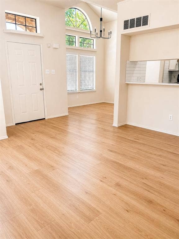 4952 Berridge Lane, Dallas, TX 75227 Vaulted ceiling with an arched window, wood-finish flooring, and a modern chandelier