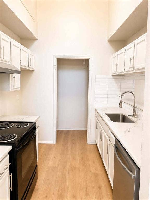 4952 Berridge Lane, Dallas, TX 75227 Kitchen featuring white cabinetry, modern hardware, stainless steel sink, subway tile backsplash, and wood-finish flooring