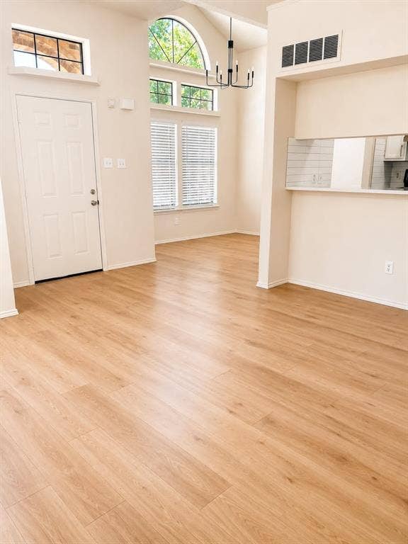 4952 Berridge Lane, Dallas, TX 75227 Vaulted ceiling, wood-finish flooring, arched window, modern chandelier, and white subway tile backsplash