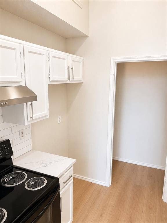 4952 Berridge Lane, Dallas, TX 75227 White cabinetry with brushed nickel hardware, stainless steel range hood, stone-finish countertop, white subway tile backsplash, and wood-finish flooring