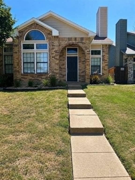 4952 Berridge Lane, Dallas, TX 75227 Brick facade with an arched entry, prominent chimney, and a front walkway