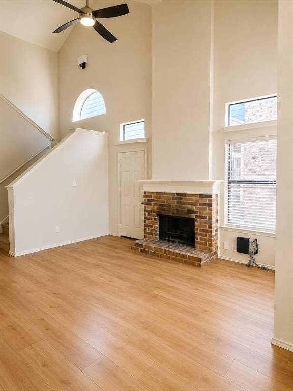 4952 Berridge Lane, Dallas, TX 75227 Vaulted ceiling with ceiling fan, wood-finish flooring, brick fireplace, and multiple windows