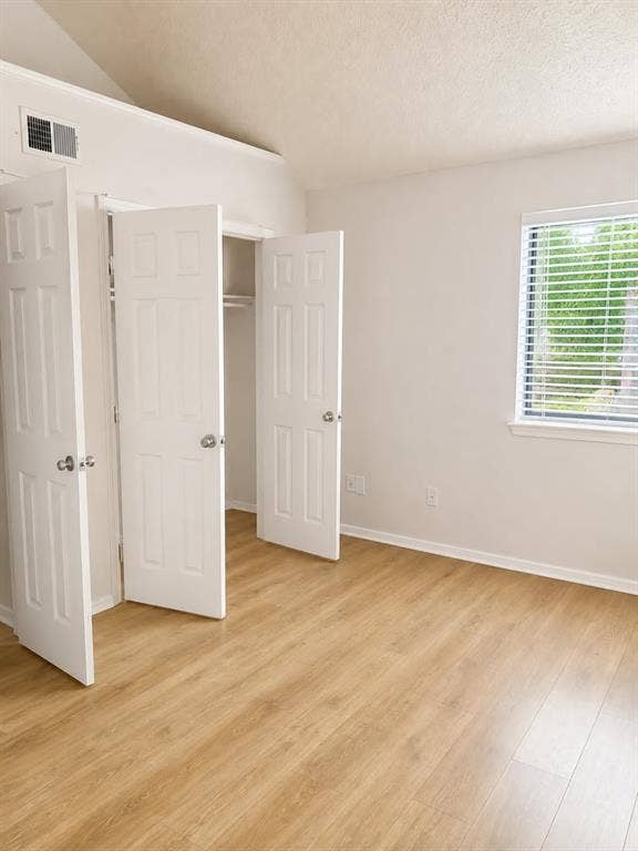 4952 Berridge Lane, Dallas, TX 75227 Vaulted ceiling with an integrated air vent, wood-finish flooring, and a window with horizontal blinds
