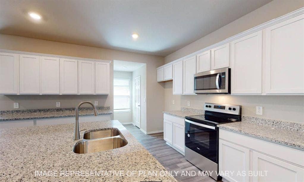 10217 Neptune Court, Waco, TX 76708 Kitchen featuring expansive light-toned countertops, white cabinetry, stainless steel appliances, and a double basin sink with a high-arc faucet